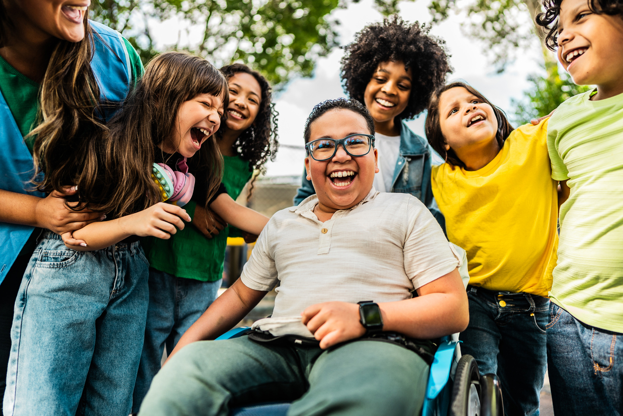 Happy students on schoolyard- including a wheelchair boy